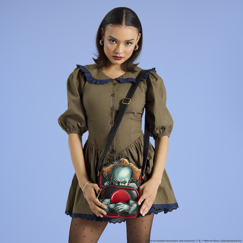 Woman wearing a polka dot dress wearing the Loungefly IT Pennywise Crossbuddies bag. 