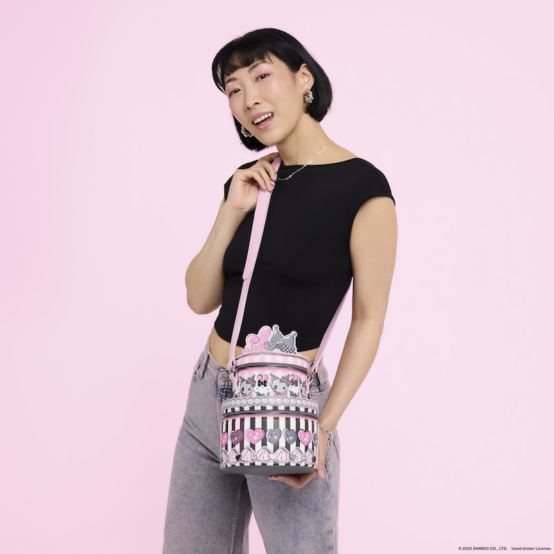 Woman wearing a black top and light-wash jeans posing for camera wearing the Loungefly Sanrio My Melody & Kuromi figural cake crossbody bag. She stands against a light pink background.