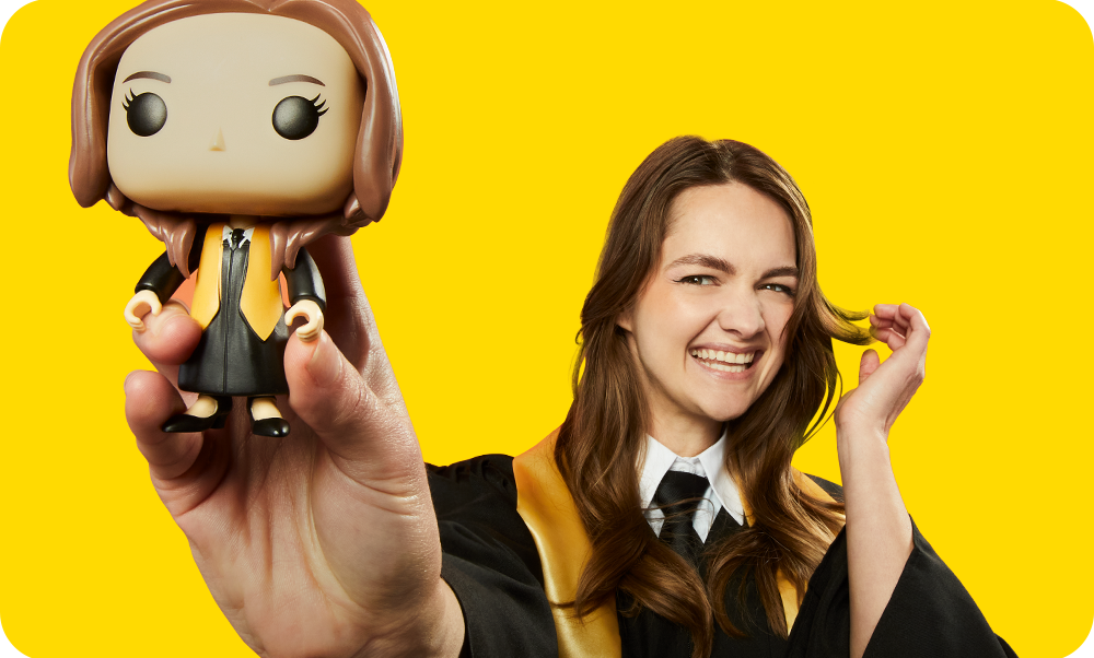 Yellow background with grad showing off her custom Funko POP! Yourself vinyl figure wearing graduation cap and gown accessories
