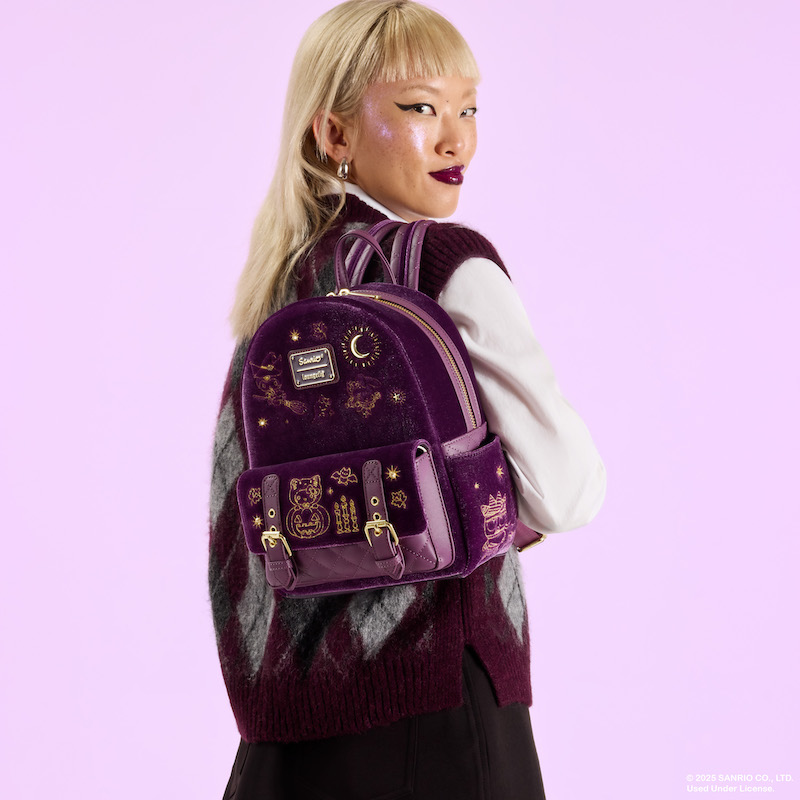 Woman looking over her shoulder, wearing a white long sleeve top under a vest, wearing the Loungefly Sanrio Hello Kitty and Friends Halloween Costume mini backpack. She stands against a purple background. 
